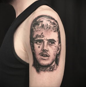 Фото тату на плече с изображением портрета Lil Peep, выполненное в реалистичном стиле с использованием черно-серых оттенков и детализированной проработкой.