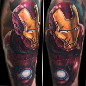 Фото тату с изображением шлема Iron Man на предплечье, выполненное в ярких цветах с реалистичной детализацией и эффектом потертости.