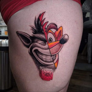 Фото татуировки с изображением Crash Bandicoot и TNT ящика. Цветная татуировка на бедре, выполненная в мультяшном стиле.