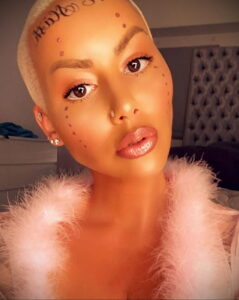 Крупный план лица Amber Rose с татуировкой 'Killa Kill' на лбу и искусственными веснушками. Она смотрит прямо в камеру.