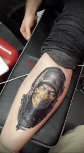 Фото татуировки Скорпиона из Mortal Kombat на икре. Реалистичный рисунок с детальной проработкой маски и костюма персонажа.