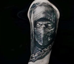 Фото черно-белой татуировки Скорпиона из Mortal Kombat на руке. Детализированное изображение лица и маски персонажа с использованием теней и контуров.