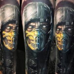 Фото реалистичной татуировки Скорпиона из Mortal Kombat на руке. Детализированное изображение лица и маски персонажа с яркими цветами и тенями.