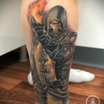 Фото тату Скорпиона из Mortal Kombat на ноге. Детализированный рисунок с изображением персонажа, выпускающего огненный шар.