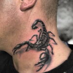 Фотография татуировки скорпиона на шее с высокой степенью реализма. Детализированная проработка текстуры тела, клешней и жала. Черно-серые тона.