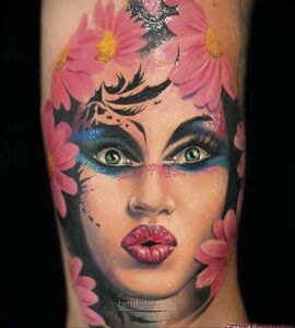 Фото тату портрета девушки с цветами на руке. Очень реалистичный рисунок татуировки с яркими цветами и детальной прорисовкой лица.