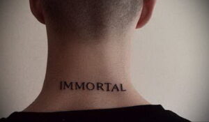 Фото минималистичной татуировки надписи 'IMMORTAL' на задней части шеи мужчины. Простой, но выразительный дизайн в черном цвете.