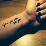 Фото тату надписи 'You get what you give' на запястье. Черный цвет, каллиграфический шрифт, минималистичный дизайн.