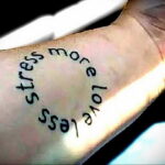 Фото тату на запястье с надписью "less stress more love". Простой и лаконичный дизайн, выполненный черными чернилами.