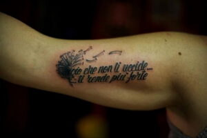 Фото тату на руке: надпись на итальянском "ciò che non ti uccide... ti rende più forte" и изображение одуванчика. Эскизы тату, мотивационные надписи.