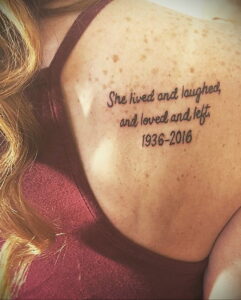 Фото тату на спине: надпись "She lived and laughed, and loved and left" с датами 1936-2016. Памятные татуировки, эскизы тату.