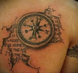 Фото татуировки компаса с надписью 'Home is where the heart is' на груди. Реалистичный рисунок татуировки с эффектом разорванной бумаги.