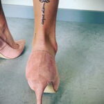 Фото тату на лодыжке с изображением цветка лотоса и надписи 'carpe diem'. Тонкие линии и минималистичный дизайн.