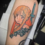 Фото тату персонажа аниме Sword Art Online на руке. Яркие цвета, детальная прорисовка лица и одежды. Отличный эскиз тату для фанатов аниме.