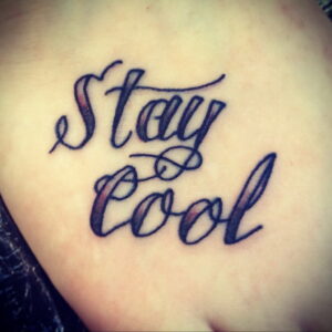Фото тату: простая, но стильная надпись "Stay Cool" на коже. Используются черные чернила и каллиграфический шрифт.