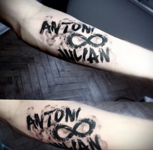 Фото тату с именами 'Anton' и 'Julian' и символом бесконечности на руке. Минималистичный дизайн в черном цвете с эффектом акварели.