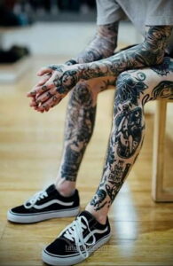 Фото полного рукава татуировок в традиционном стиле. Изображены различные рисунки: животные, цветы, надписи и символы.