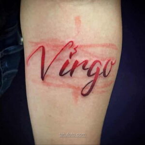 Фото акварельной татуировки надписи 'Virgo' на руке. Красный цвет и брызги краски создают эффект нежности и романтики. Эскиз тату для девушек.
