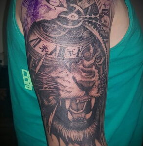 Фото тату на предплечье: самурай в шлеме с часами, выполненное в технике реализм с использованием черных и серых оттенков.