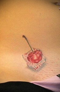 Фото тату вишни в кубике льда. Реалистичный рисунок с красной ягодой, прозрачным льдом и каплями воды. Оригинальная татуировка.