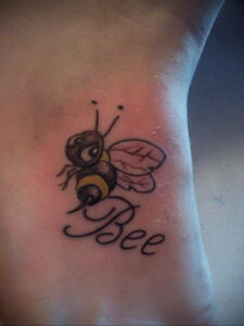 Фото тату пчелы на лодыжке с надписью 'Bee'. Небольшой рисунок татуировки с реалистичными крыльями и телом.
