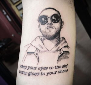 Черно-белая татуировка с портретом Мак Миллера в очках и с цитатой под ним. Выполнена в минималистичном стиле.
