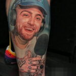 Цветное фото тату на предплечье с изображением Mac Miller в кепке, с наушниками и микрофоном, символизирующим его музыкальную карьеру.