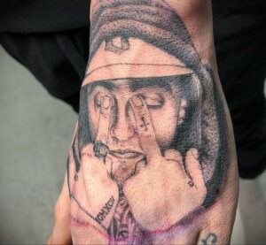 Фото тату на руке с портретом Mac Miller в задумчивом настроении. Черно-белый рисунок татуировки с детальной проработкой.