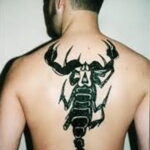 Фото простой татуировки скорпиона в стиле blackwork на спине. Четкие линии и минималистичный дизайн.