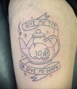 Фото тату на предплечье: чайник с черепом внутри и надписью 'Give me tea or give me death' в стиле олдскул.