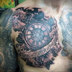 Фото тату на груди мужчины с изображением часов, ворона, розы и надписи 'Time waits for no man'. Детализированный рисунок в черно-серых тонах.