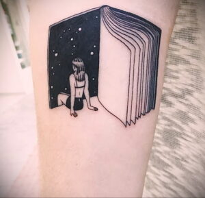 Фото тату на руке с изображением открытой книги, из которой выходит девушка в звездное небо. Сюрреалистичный и загадочный рисунок татуировки.