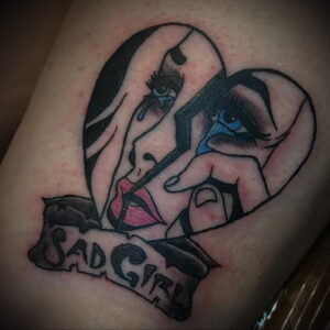 Фото тату плачущего сердца с изображением двух женских лиц и надписью "Sad Girl". Эмоциональный и выразительный рисунок.