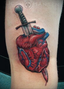 Фото реалистичной татуировки на предплечье: сердце, пронзенное мечом, с капельками крови. Детализированная проработка, реалистичные тени.