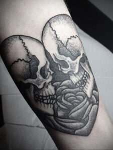 Фото тату на руке: татуировка в технике dotwork с изображением черепа, обвитого розой, выполненная в черно-белых тонах.