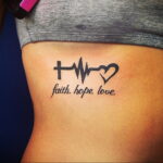 Фото татуировки на боку: пульс, крест, сердце и надпись 'Faith Hope Love'. Черно-белый рисунок, минималистичный стиль.