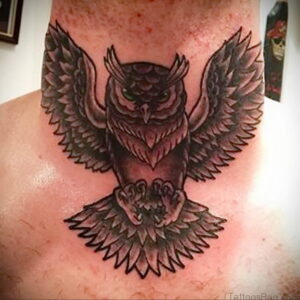Фотография черно-серой татуировки совы на шее. Тату выполнено в графичном стиле с использованием теней и линий.