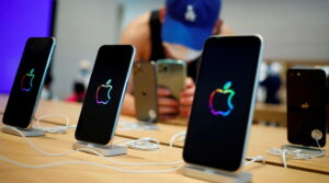 Фотография четырех iPhone с разноцветными логотипами Apple на черном фоне. Современные смартфоны, выставленные в магазине. Технологии и стиль.