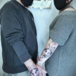 Фото парной татуировки хаски на руках мужчины и женщины, выполненной в черно-белой гамме. Мужчина и женщина демонстрируют свои татуировки.