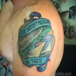 Фотография татуировки бургера с надписью 'A scale doesn't measure my taste'. Рисунок выполнен в реалистичном стиле с использованием ярких цветов и теней.