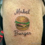Фото татуировки с изображением бургера и надписью 'Mabel Burger'. Простой и лаконичный рисунок в минималистичном стиле.