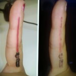 Фото татуировки на пальце с изображением Дарта Вейдера и светового меча. Небольшой, но детализированный рисунок, выполненный в черных и красных тонах.
