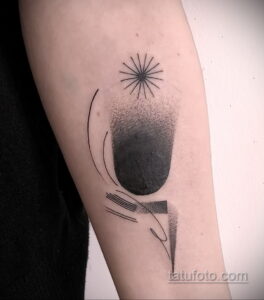 Фото абстрактной татуировки на предплечье, изображающей падающую звезду в геометрическом стиле. Черно-белый рисунок татуировки с использованием точек и линий.