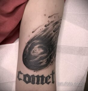 Фото тату: реалистичная татуировка кометы с надписью "Comet" на предплечье. Детализированный рисунок татуировки в черно-серых тонах.
