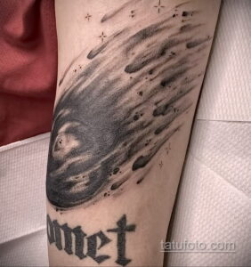 Фото тату: реалистичная татуировка кометы с надписью "Comet" на предплечье. Детализированный рисунок татуировки в черно-серых тонах.