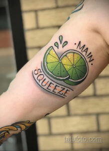 Фото тату на руке: половинка лайма с надписью 'Main Squeeze'. Яркие цвета, четкие контуры, традиционный стиль.
