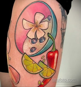 Фото тату на бедре: яркий рисунок с перцем чили, лаймом, цветком и брызгами. Насыщенные цвета и детальная проработка.