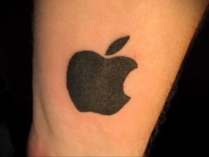 Фото тату: простой и стильный рисунок логотипа Apple на руке, выполненный в черном цвете. Идеальный эскиз тату для поклонников бренда.