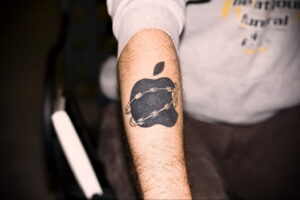 Фото минималистичной татуировки с изображением логотипа Apple, покрытого трещинами. Простой и стильный рисунок татуировки.