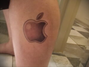 Фото реалистичной татуировки с изображением логотипа Apple на ноге. Детализированный рисунок татуировки.